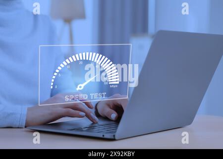 Test de vitesse. Femme utilisant un ordinateur portable à table, gros plan. Écran virtuel sur l'appareil Banque D'Images