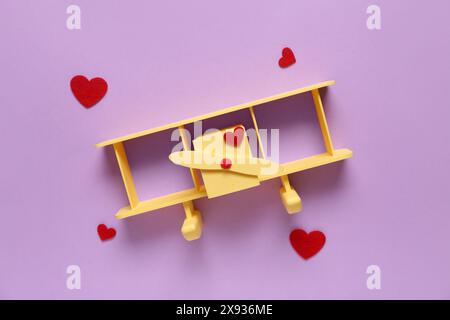 Avion jouet avec des coeurs sur fond lilas. Célébration de la Saint-Valentin Banque D'Images