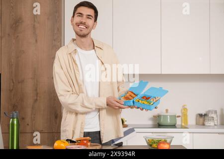 Jeune homme avec boîte à lunch dans la cuisine Banque D'Images