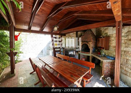 Tables et bancs dans un gazebo en bois avec un poêle et des armoires de cuisine Banque D'Images