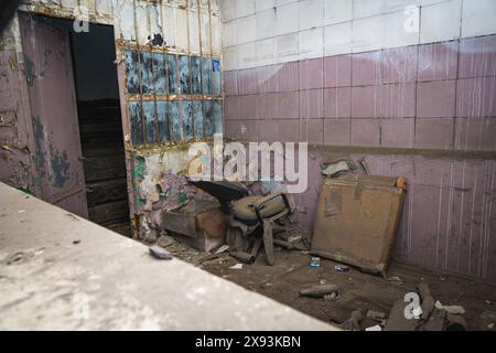 Vieille salle de ruine couverte de poussière avec chaise cassée dans un bâtiment abandonné désolé Banque D'Images