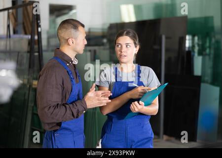 Ouvrière d'usine de verre discutant des tâches de travail avec le maître dans l'atelier Banque D'Images