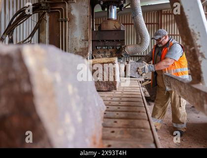 Mittweida, Allemagne. 28 mai 2024. Un employé de Natursteinwerk Mittweida GmbH travaille à la fendeuse de pierres. Le granit Mittweida avec sa coloration rougeâtre est extrait ici depuis 140 ans. La pierre est proposée comme matériau en vrac comme la pierre concassée et les gravillons ou comme pierre de construction sous forme de pavés ou pour murs. Crédit : Jan Woitas/dpa/Alamy Live News Banque D'Images