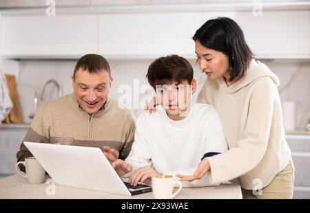 Une famille amicale regarde quelque chose ensemble sur Internet ou des chats vidéo via un ordinateur portable Banque D'Images