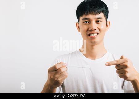 L'homme asiatique se brosse les dents le matin, tient une brosse à dents, sourit et pointe Banque D'Images