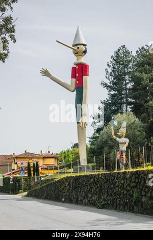 La plus haute statue de Pinocchio au monde dans la ville médiévale historique de Collodi en Toscane, avec un visage, un nez, une main et un corps en bois par temps nuageux. Banque D'Images