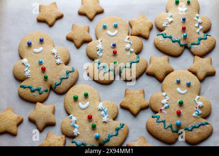 De petits hommes en pain d'épice décorés de Noël sont allongés sur la table. La cuisson de Noël bat son plein Banque D'Images