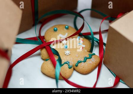 De petits hommes en pain d'épice décorés de Noël sont allongés sur la table près des boîtes en carton, prêts à être emballés. Banque D'Images