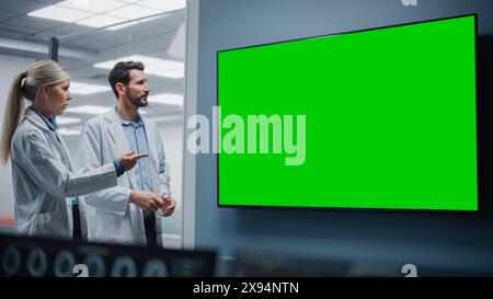 Réunion de laboratoire de l'hôpital de neurosciences médicales : neurochirurgien et neurologue utilisent Green Screen Chroma Key TV, parler de la méthode de traitement des patients malades, médicaments avancés, recherche en biotechnologie de haute technologie Banque D'Images