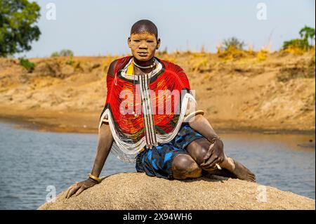 Femme Mundari dans une robe traditionnelle avec le visage couvert de cendres posant sur un rocher, tribu Mundari, Soudan du Sud, Afrique Banque D'Images