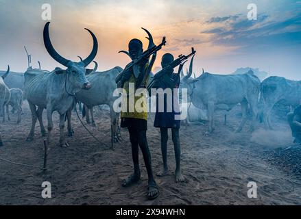 Jeunes garçons avec Kalachnikov posant avec des vaches, tribu Mundari, Soudan du Sud, Afrique Banque D'Images