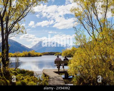 Couple sur un banc donnant sur le lac Wakatipu, région d'Otago, Île du Sud, Nouvelle-Zélande, Pacifique Banque D'Images