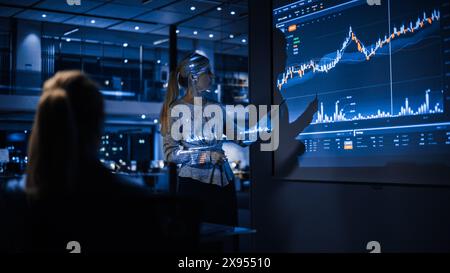Présentation de la réunion de la conférence d'affaires : la femme d'affaires fait l'analyse financière parle à un groupe de gens d'affaires. L'écran du projecteur affiche les données boursières, la stratégie d'investissement et la croissance des revenus Banque D'Images