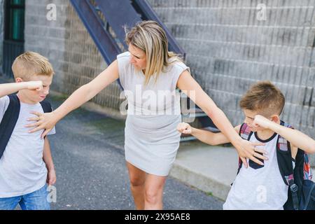 L'arrêt de l'enseignant Deux Garçons Lutte In Playground Banque D'Images