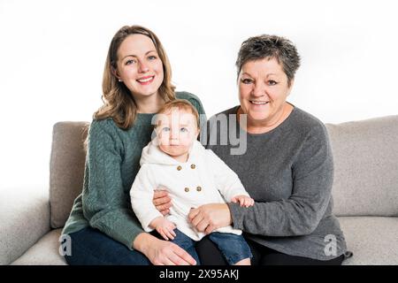 Heureuse petite fille positive assise sur les genoux de grand-mère avec sa mère Banque D'Images