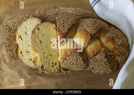 Pain Challah tressé traditionnel en tranches fait maison sur du papier sulfurisé décoré de graines de sésame, boulangerie juive traditionnelle tranchée pour le Shabbat Banque D'Images