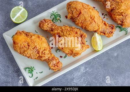 Pilons de poulet frit sur une assiette garnie de romarin frais et citron Top Down photo Banque D'Images