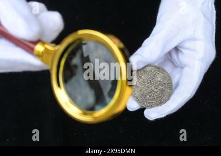 29 mai 2024, Saxe-Anhalt, Wettin-Löbejün : une des 285 pièces d'argent récupérées sous la loupe. Lors des travaux de construction d'une ferme historique dans la Brauhausgasse de Wettin, une grande trouvaille de monnaies du XVIIe siècle a été découverte. Au moment du dépôt des pièces, la maison appartenait à Johann Dondorf, l'un des citoyens les plus riches de Wettin, qui était maire de la ville à l'époque. Photo : Heiko Rebsch/dpa Banque D'Images