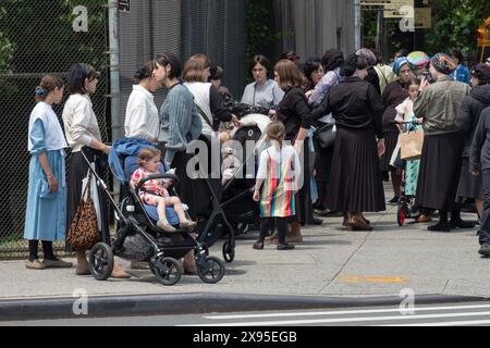 Un groupe de femmes juives orthodoxes et leurs filles attendent devant aa Shool pour regarder les célébrations de l'holicday de Lag B'Omer. À Brooklyn, New York. Banque D'Images