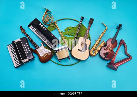 Journée mondiale de la musique. Assortiment d'instruments de musique avec carte du monde sur fond bleu Banque D'Images