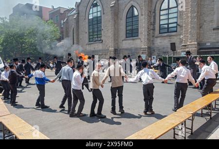 Les étudiants juifs orthodoxes célèbrent Lag B'Omer en dansant près d'un feu traditionnel. Dans une rue fermée à Brooklyn, New York. Banque D'Images
