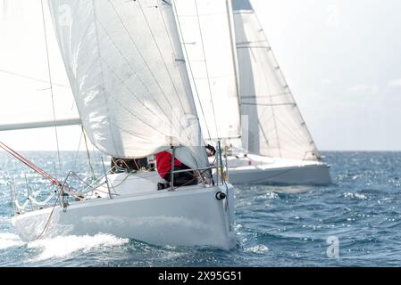 Deux yachts aux voiles gonflantes s'affrontent dans une régate sur l'océan scintillant Banque D'Images