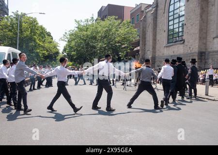 Les étudiants et enseignants juifs orthodoxes célèbrent Lag B'Omer en dansant près d'un feu traditionnel. Dans une rue fermée à Brooklyn, New York. Banque D'Images
