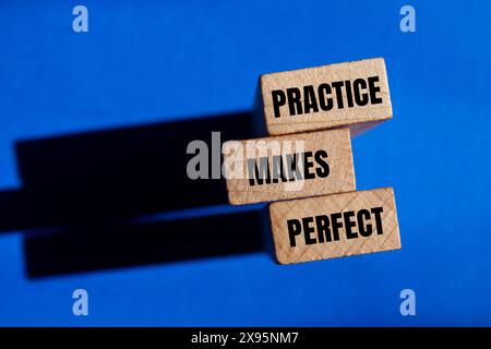 La pratique fait des mots parfaits écrits sur des blocs de bois avec un fond bleu. La pratique conceptuelle rend le symbole parfait. Copier l'espace. Banque D'Images