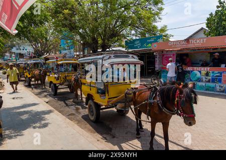 Des charrettes à chevaux traditionnelles (Cidomo) attendent à côté du port sur la rue principale de l'île Gili Trawangan à In Banque D'Images