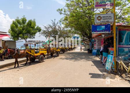Des charrettes à chevaux traditionnelles (Cidomo) attendent à côté du port sur la rue principale de l'île Gili Trawangan à In Banque D'Images