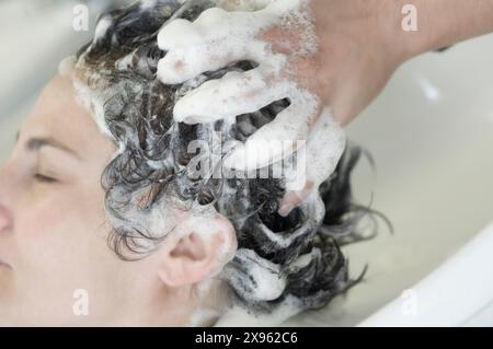 Cute femme ayant les cheveux lavés dans un salon de coiffure Banque D'Images