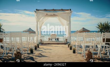 Espace de mariage vide décoré en plein air avec chaises pour cérémonie officielle sur une plage près de la mer ou de l'océan. Tout préparé pour de belles célébrations de mariage romantique. Les clients arrivent bientôt. Banque D'Images