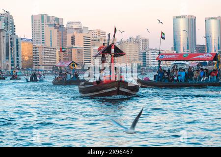 Dubaï, Émirats arabes Unis - 6 janvier 2024 : bateaux traditionnels sur fond de gratte-ciel imposants, incarnant l'esprit dynamique de Dubaï. Banque D'Images