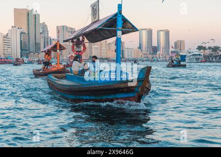 Dubaï, Émirats arabes Unis - 6 janvier 2024 : un bateau abra traditionnel navigue sur fond de toits modernes de Dubaï, soulignant la dualité culturelle de la ville. Banque D'Images