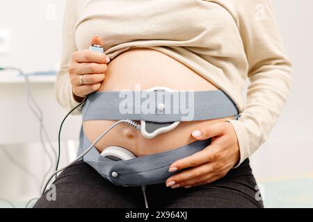 Femme enceinte vérifiant le rythme cardiaque fœtal par surveillance fœtale. Mère enceinte avec sage-femme qui ajuste les capteurs hors cardiotocographie (CTG). Banque D'Images