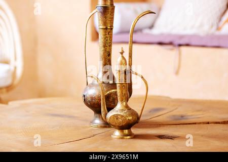 Deux vases en laiton sont élégamment placés sur une table en bois rustique, créant une pièce de décoration charmante et élégante Banque D'Images