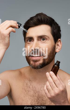 Homme musclé sans chemise tenant une bouteille de sérum. Banque D'Images