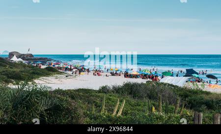 Des foules de spectateurs se détendent sous des parasols colorés sur un rivage de sable, plage de Grumari, Rio de Janeiro Banque D'Images