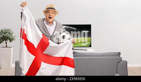 Fan de football tenant un drapeau anglais et soutenant une équipe depuis chez lui Banque D'Images