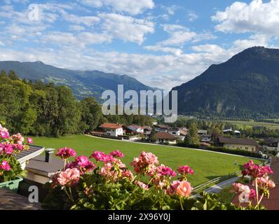 Vue idyllique depuis le balcon avec des fleurs de géranium dans le village de Wiesing vers la vallée verdoyante avec les Alpes et le lac Achensee dans le Tyrol, Autriche. Été s Banque D'Images