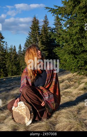 Belle fille chamanique jouant sur le tambour de cadre de chaman dans la nature. Photo de haute qualité Banque D'Images