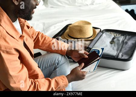 Gros plan à angle élevé de l'homme afro-américain emballant le passeport et les documents dans la valise et se préparant pour l'espace de copie de voyage Banque D'Images