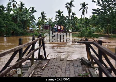 Assam, Inde. 29 mai 2024. Les villageois regardent un pont détruit après de fortes pluies suite à la chute du cyclone Remal dans le district de Nagaon, Assam, dans le nord-est de l’Inde, le 29 mai 2024. Les tempêtes et les glissements de terrain provoqués par les pluies déclenchés à la suite du cyclone Remal ont tué au moins 32 personnes et en ont blessé de nombreuses autres à travers le Bengale occidental de l'Inde et quatre états du nord-est, ont déclaré mardi des responsables. Crédit : Str/Xinhua/Alamy Live News Banque D'Images
