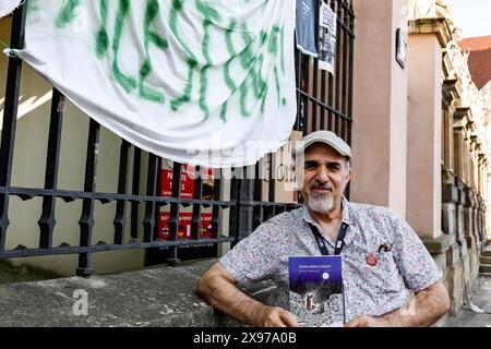 28 mai 2024, Cracovie, Malopolskie, Pologne : Nidal Hamad montre un livre avec des histoires de victimes de guerre palestiniennes alors que les étudiants de l'Université Jagiellonia font grève dans la cour du Collegium Broscianum pendant une semaine en soutien à la Palestine. Les étudiants ont organisé une grève pacifique contre Israël attaque contre la Palestine. Les étudiants polonais ont protesté contre ce qu’ils appellent un génocide alors que plus de 35 000 Palestiniens ont été tués dans ce conflit de 7 mois. Israël a attaqué la bande de Gaza après que le Hamas s’est infiltré et a tué plus de 11 cents personnes en Israël le 7 octobre 2023. (Crédit image : © Dominika Zarz Banque D'Images