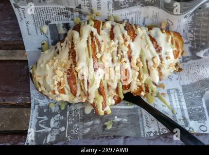 Pâtisserie de croissant avec crème vanillée sur le dessus placé sur le journal Banque D'Images