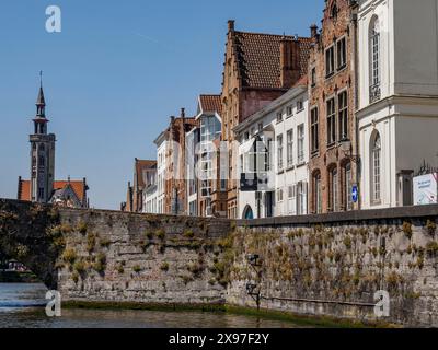 Pont de pierre et façades historiques avec vue sur une tour d'église le long d'un canal sous un ciel bleu, ville historique au bord de la rivière avec des pignons ornés, ancien Banque D'Images