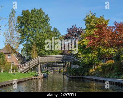 Une rivière tranquille avec un pont en bois voûté et un feuillage couleur automne, de petits ponts en bois sur les canaux aux pays-Bas, des maisons et des arbres sur Banque D'Images