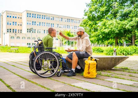 Photo intégrale d'un étudiant universitaire adulte caucasien nourrissant un ami atteint de paralysie cérébrale sur le campus Banque D'Images