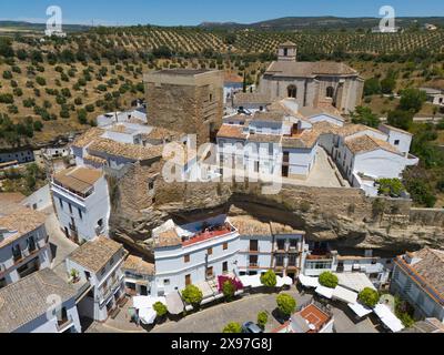 Village espagnol avec bâtiments historiques, église et oliveraies sous un ciel ensoleillé, entouré d'un mur de pierre, vue aérienne, habitations de grotte, Setenil Banque D'Images