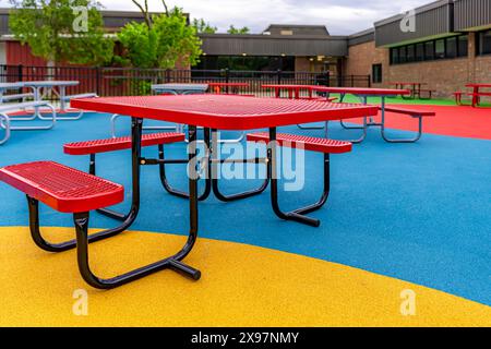 ADA revêtu de vinyle rouge, fauteuil roulant, table de pique-nique accessible sur une surface de jeu multicolore. Banque D'Images